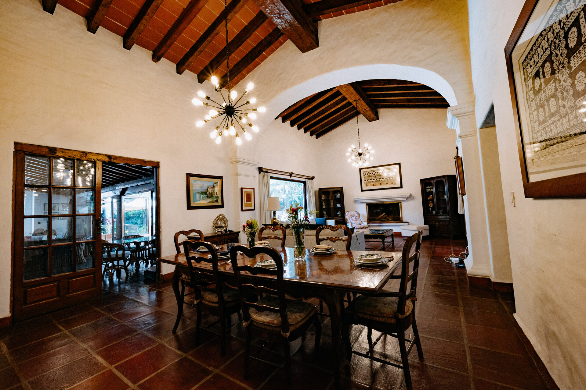 Sala y comedor de Quinta La Joya bajo bóveda de ladrillo con vigas de madera, chimenea de cantera y ventanales al jardín
