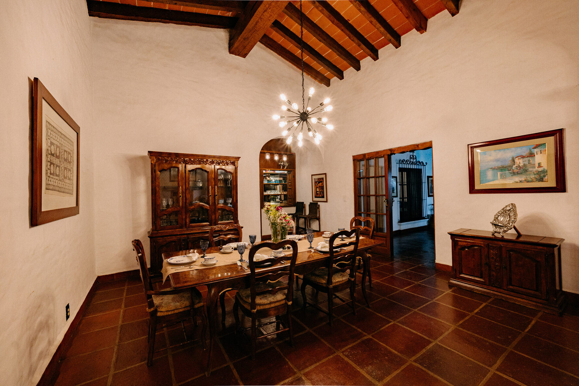 Comedor formal de Quinta La Joya con mesa de madera, vitrina y techo de viga