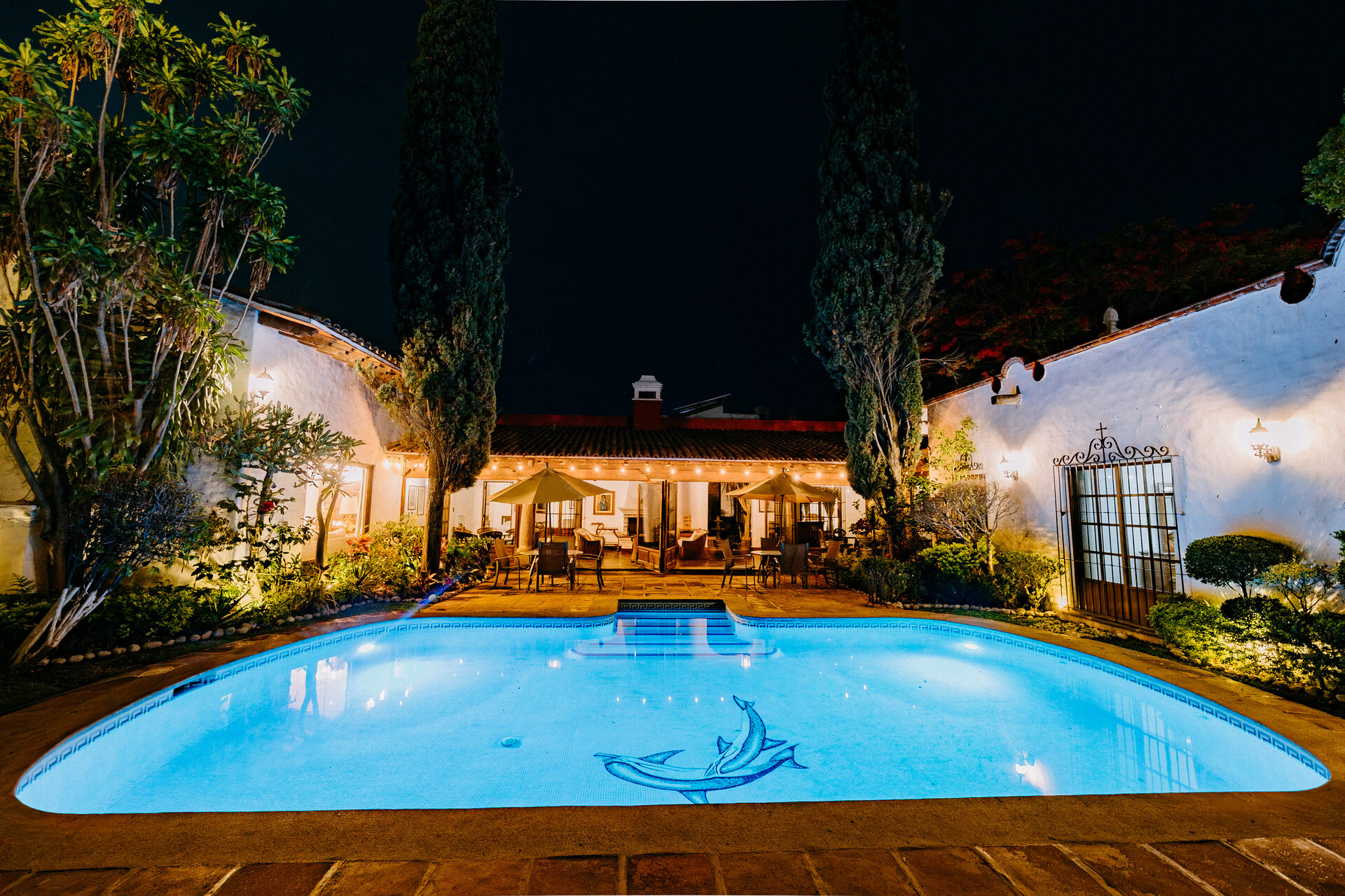 Alberca iluminada de Quinta La Joya al anochecer con la casa colonial y su terraza al fondo