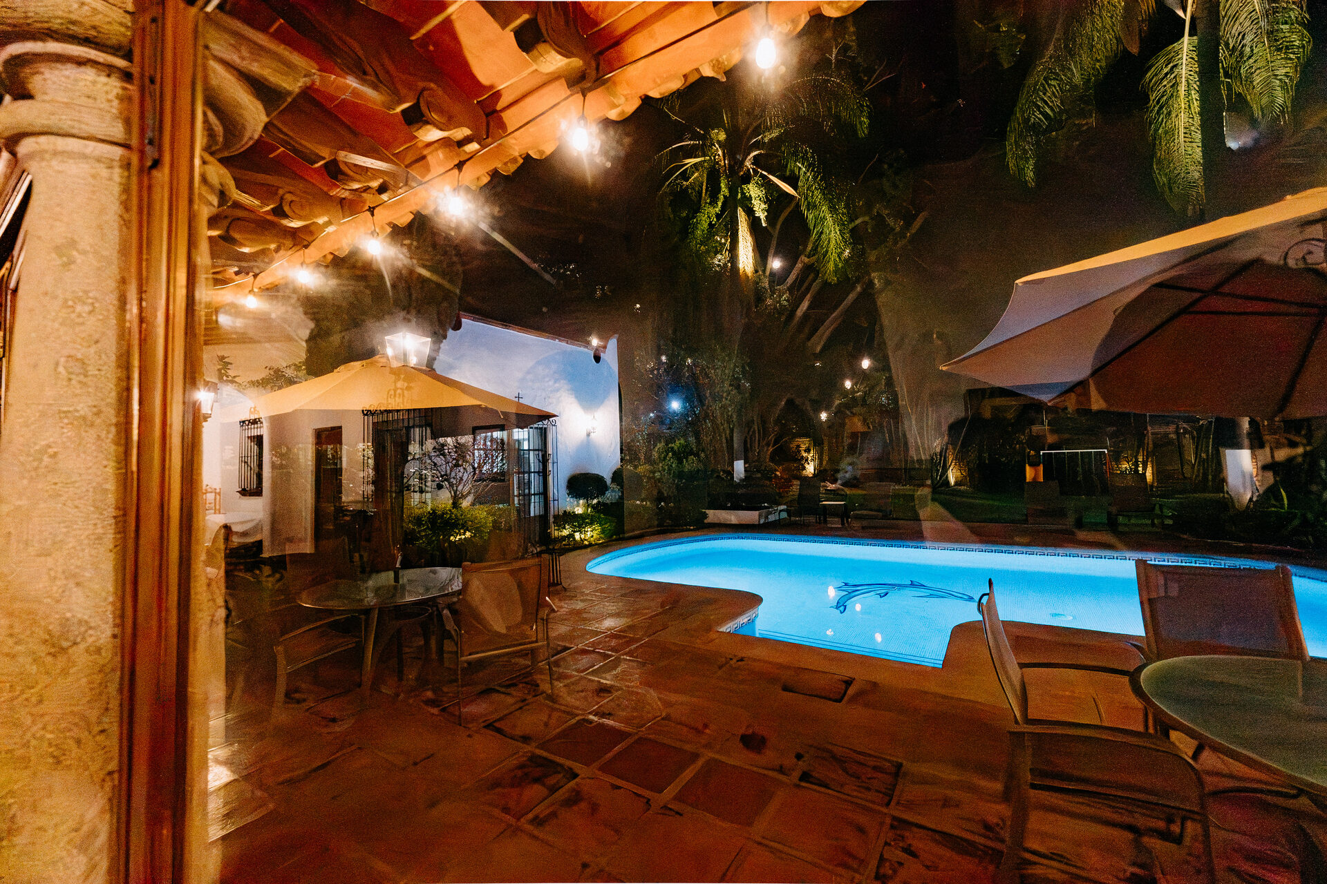 Terraza de Quinta La Joya de noche vista desde el interior, con faroles encendidos y la alberca al fondo