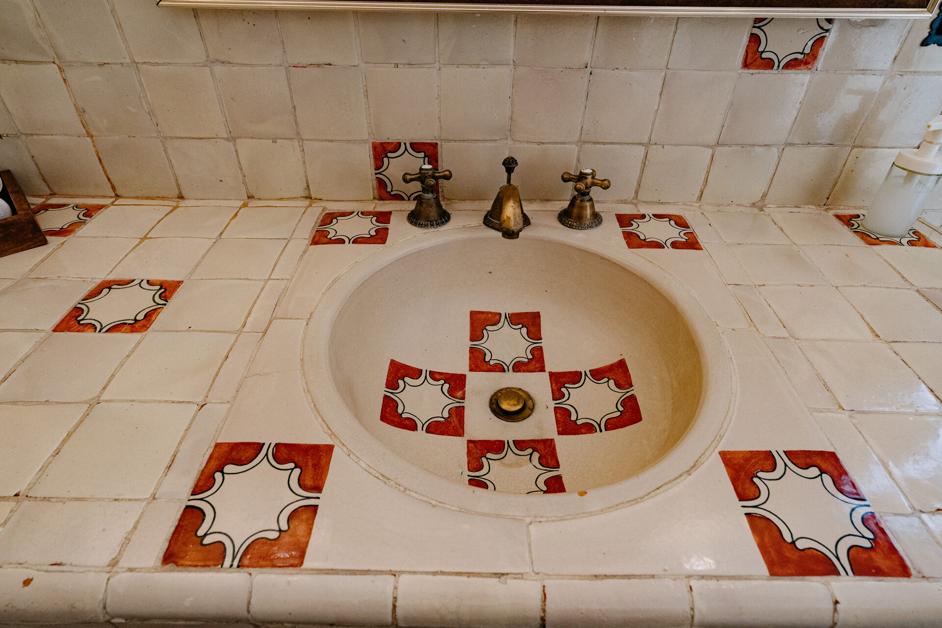 Lavabo de talavera pintado a mano con motivo floral rojo y azul, en el baño de la recámara principal de Quinta La Joya