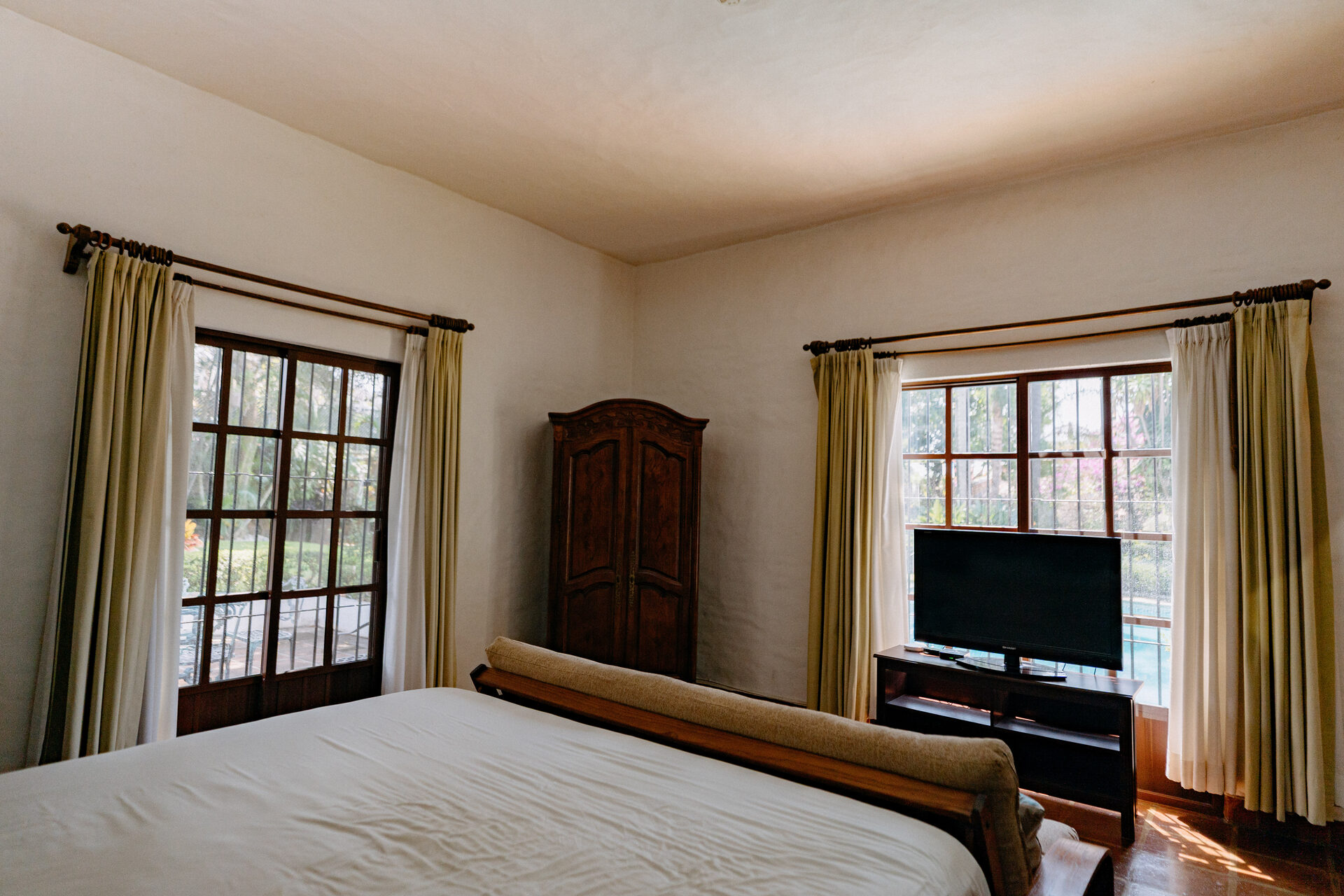 Recámara principal de Quinta La Joya con ventanales al jardín, armario de madera y piso de barro