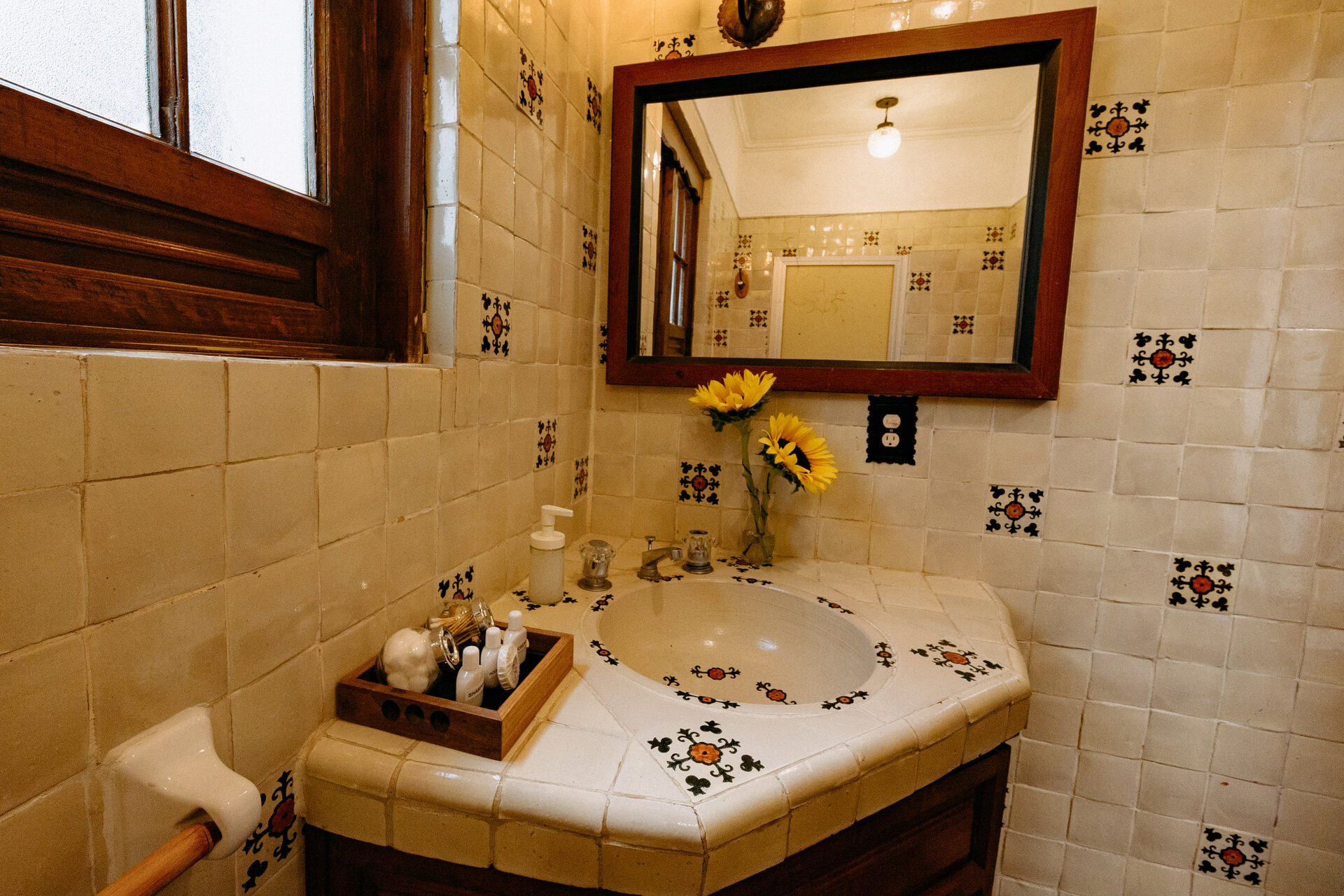 Baño de la suite 3 de Quinta La Joya con azulejo pintado a mano en ocre y negro y espejo de madera