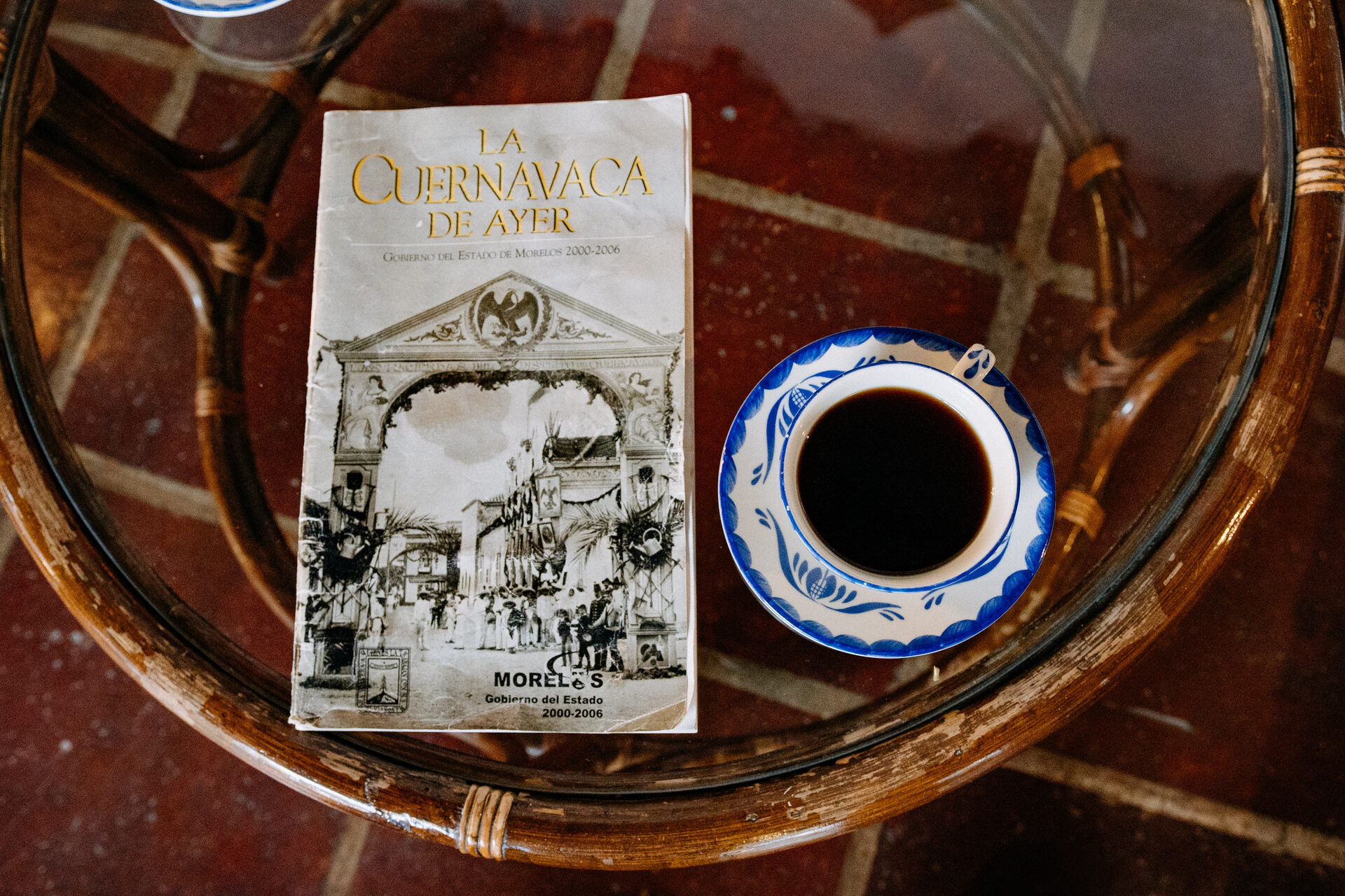 Taza de café y un libro sobre La Cuernavaca de Ayer en la mesa de cristal de la terraza de Quinta La Joya